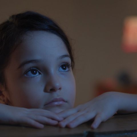 Uma menina apoiada em uma janela olha para o céu