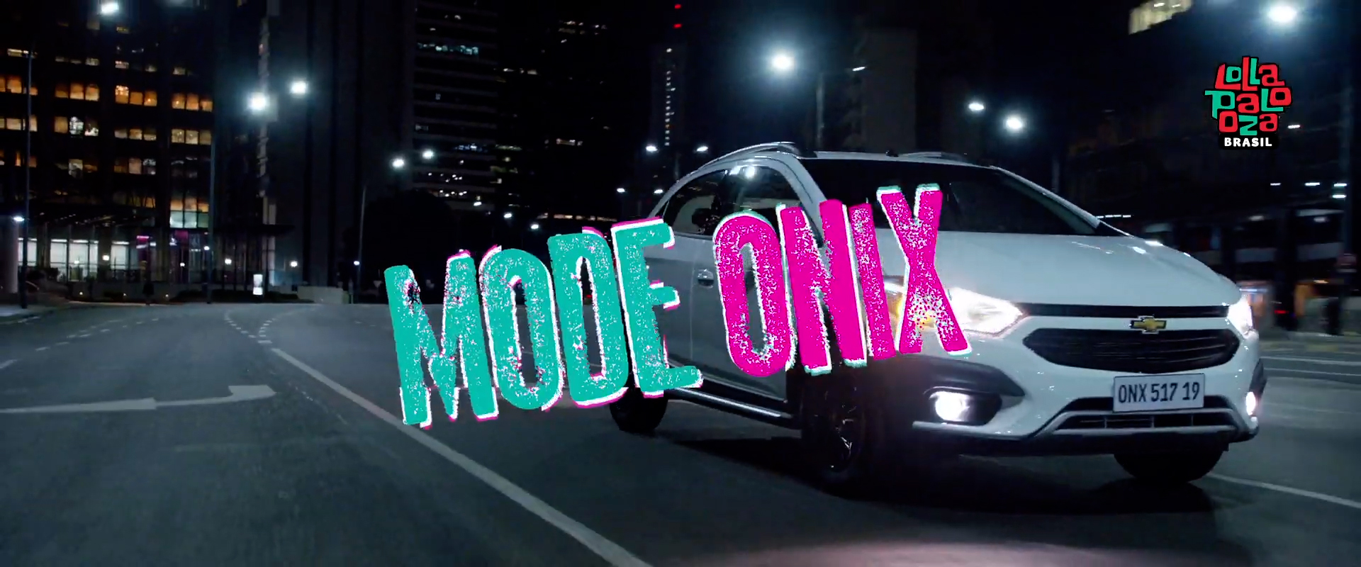 À noite, o Chevrolet Onix percorre uma rua. Há o logo Lollapalooza e o texto: Mode Onix