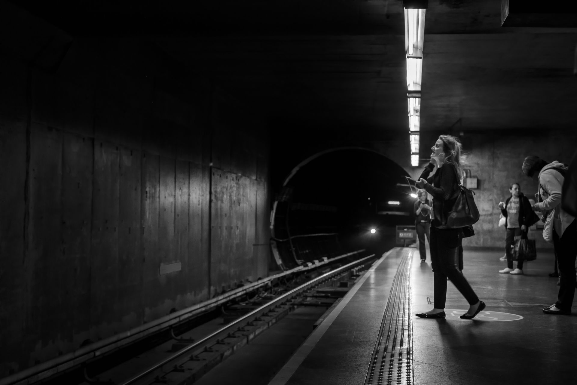 Uma mulher escuta música enquanto espera um trem.